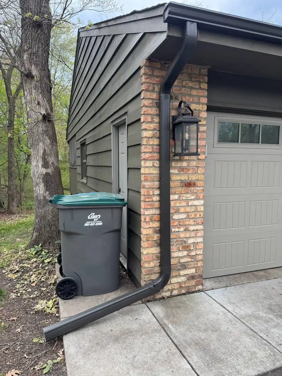 Dark brown custom seamless gutter on a brick garage column in Eden Prairie.
