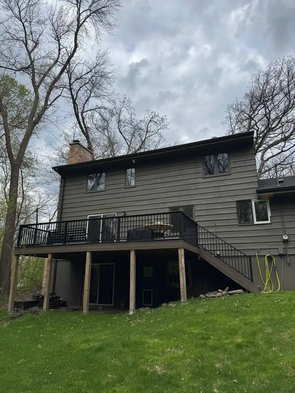 Dark custom seamless gutters installed on a home with a deck and walkout basement in a heavily wooded Eden Prairie neighborhood.