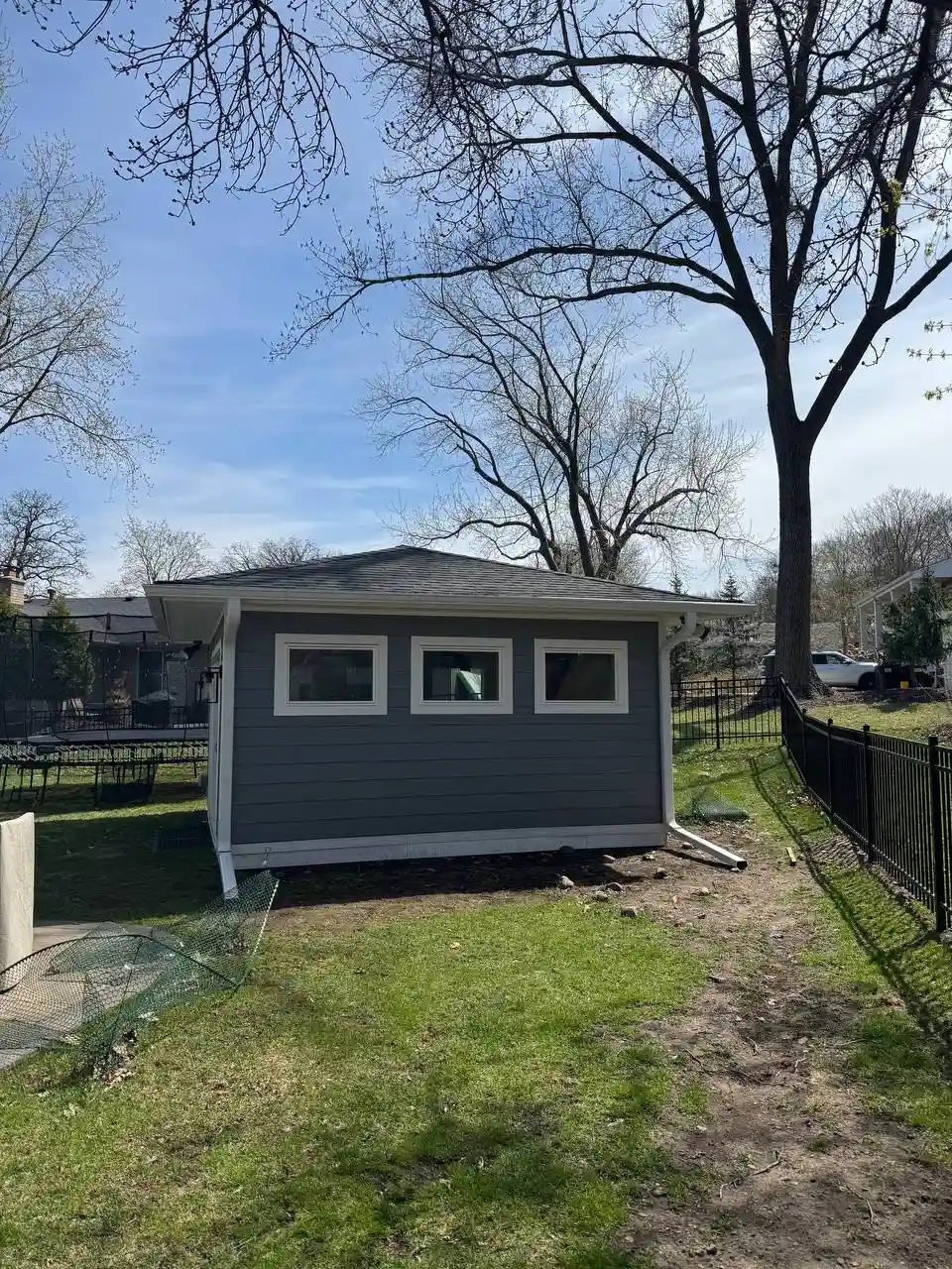 White seamless gutter installation on a backyard shed in Eden Prairie, designed to protect the structure from water damage under overhanging trees.
